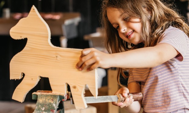 Kind raspelt an Holzfigur