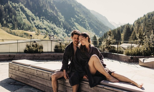 Ein Paar entspannt sich im Außenbereich eines Whirlpools mit Bergblick.