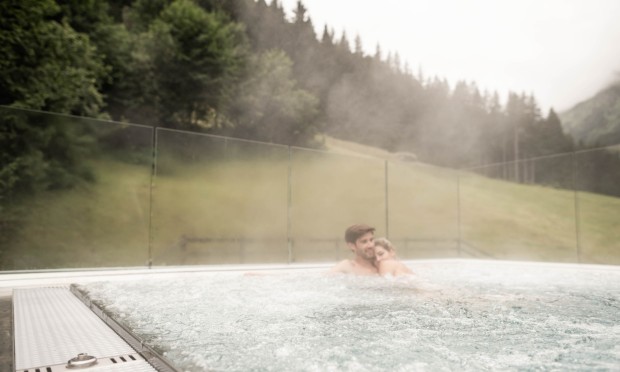 Eine Person genießt ein Outdoor-Thermalbad mit Blick auf die Natur.