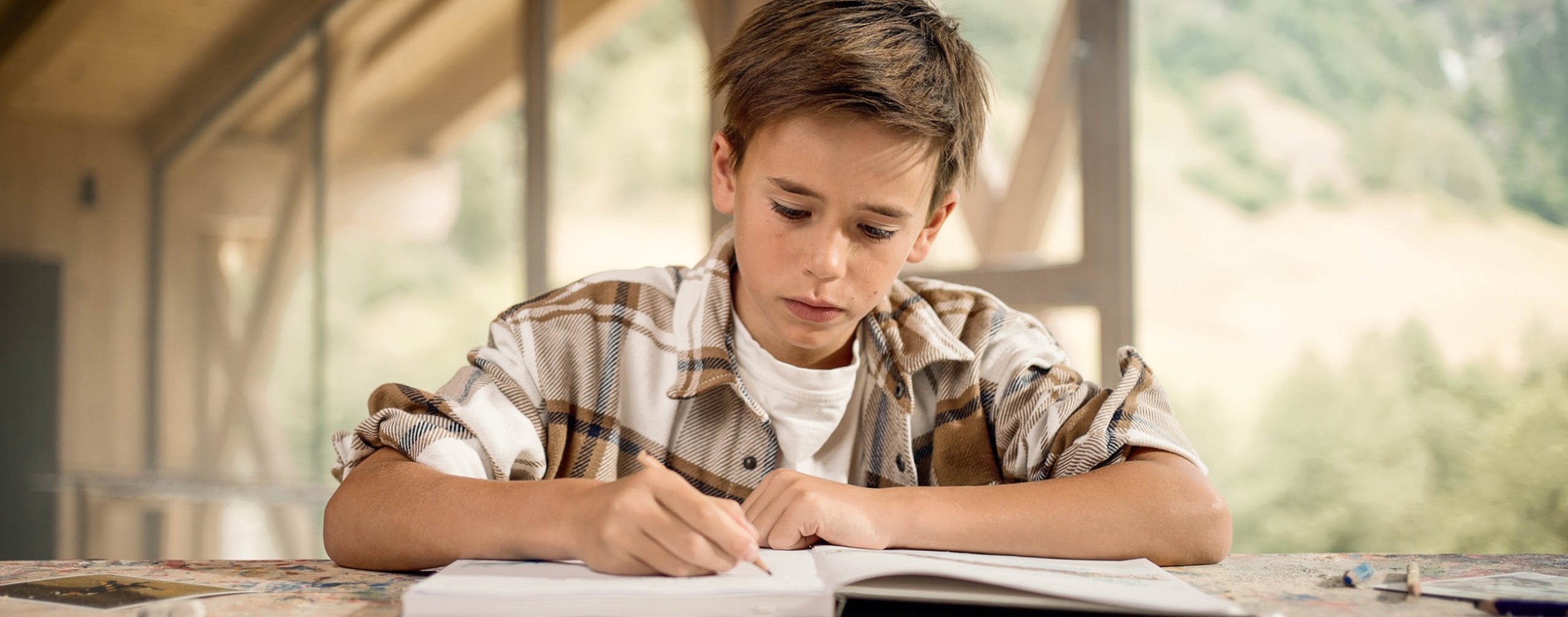 Kind in der Holzwerkstatt schreibt Tagebuch im Familienhotel Feuerstein in Südtirol