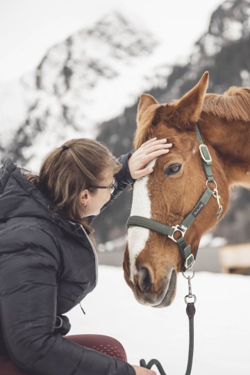 Reitlehrerin streichelt Pferd im Freien