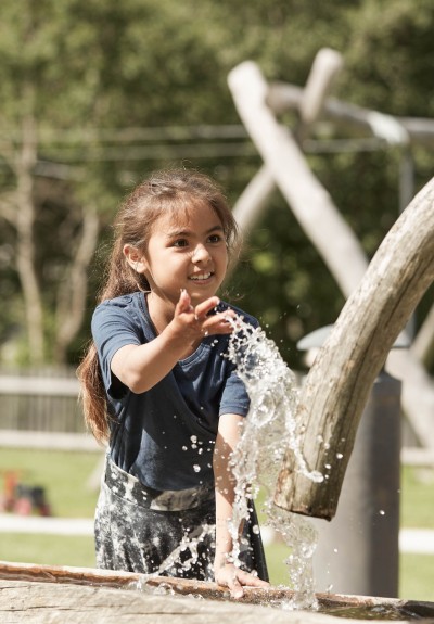Girl is playing with water from a fountain