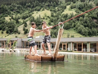 2 Jungs ziehen sich auf Floß über den Teich