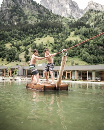 2 Jungs ziehen sich auf Floß über den Teich