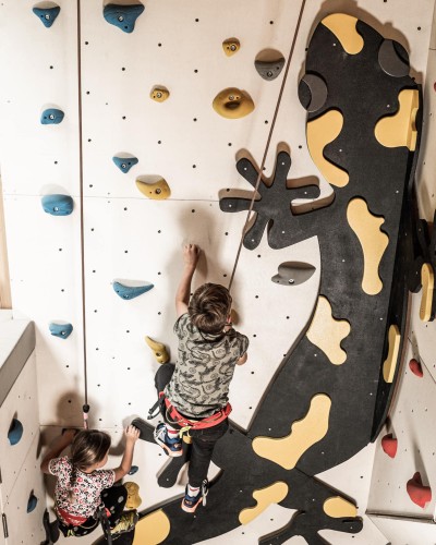 2 Kinder klettern eine Kletterwand hinauf