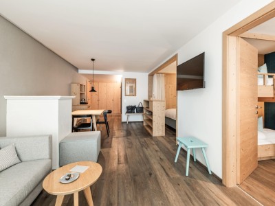 Raum mit Couch, Fernseher, kleiner Küchentisch und Stockbett in eigenem Zimmer