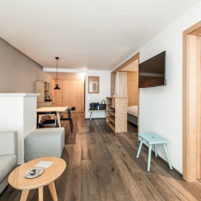 Raum mit Couch, Fernseher, kleiner Küchentisch und Stockbett in eigenem Zimmer