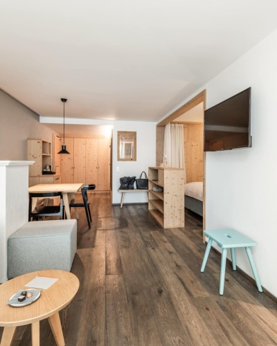 Raum mit Couch, Fernseher, kleiner Küchentisch und Stockbett in eigenem Zimmer