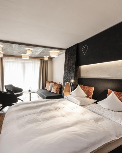 Hotelzimmer mit rundem Tisch und 2 Sessel und großes Doppelbett