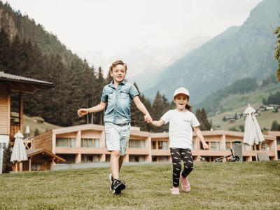 2 Kinder laufen über die Wiese vor dem Hotel