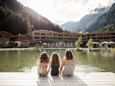 3 kleine Mädchen sitzen am Rande des Teiches