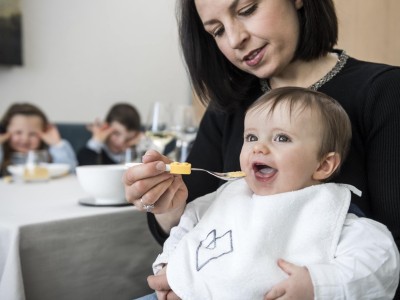 Kleines Kind auf dem Schoß der Mutter wird gefüttert