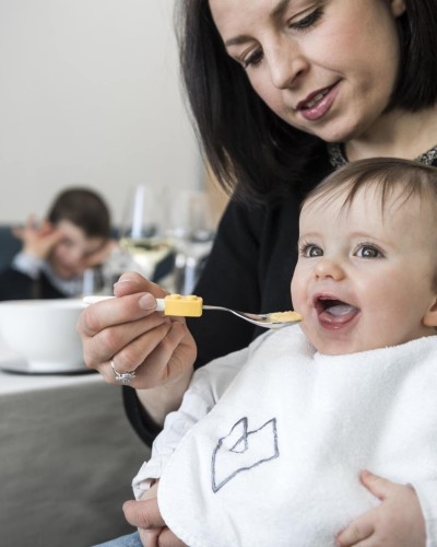 Kleines Kind auf dem Schoß der Mutter wird gefüttert