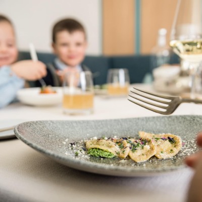 3 Schlutzkrapfen auf einem Teller und im Hintergrund 2 Kinder