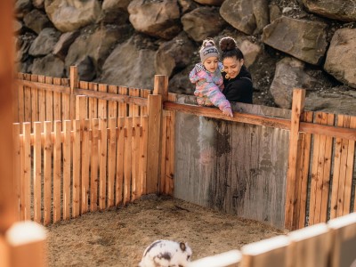 Kleines Mädchen wird von Frau gehalten und zeigt auf ein kleines Kanninchen