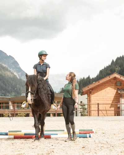 Reitlehrerin geht mit Pferd und Reitschülerin spazieren