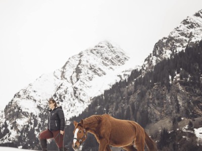 Reitlehrerin geht mit Pferd im Schnee spazieren