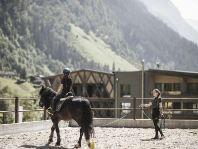 Reitlehrerin führt Pferd mit Kind