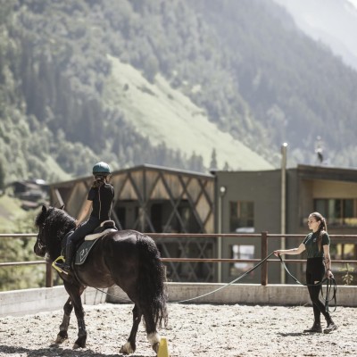 Reitlehrerin führt Pferd mit Kind
