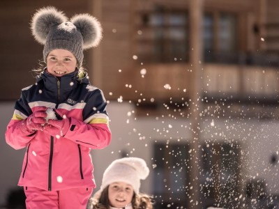 2 Mädchen in Winterklamotten spielen im Schnee