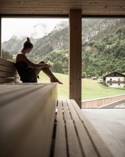 Frau sitzt im Sauna Bereich und beobachtet den Außenbereich