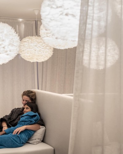 Mutter und Tochter liegen entspannt beieinander, beide in einem Bademantel eingewickelt