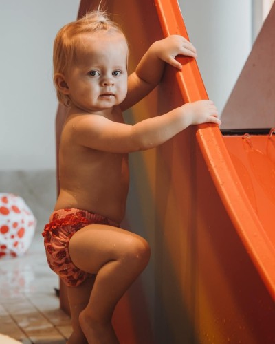 Kleinkind stützt sich an der kleinen Wasserrutsche für Kinder