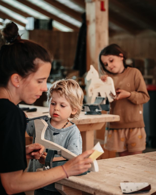 Kind in Holzwerkstatt mit Eltern