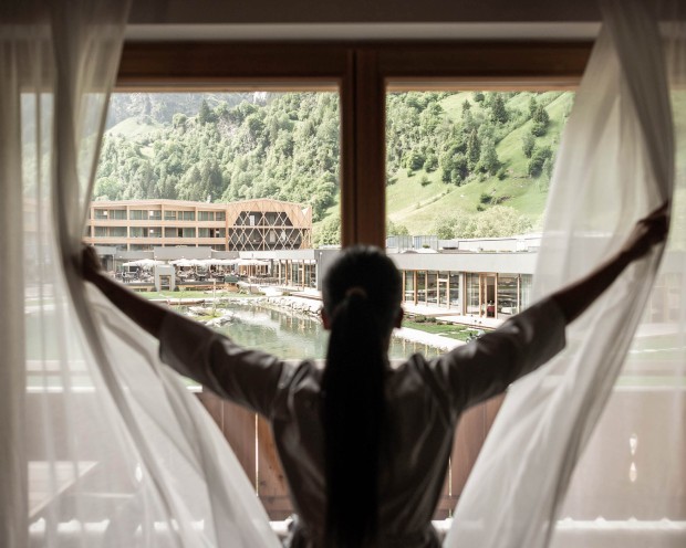Putzfrau öffnet Vorhang eines Zimmers mit Aussicht auf das Feuerstein