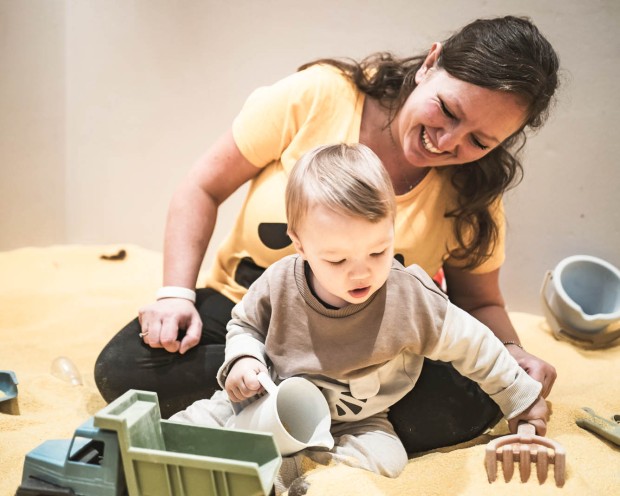 Mutter und Kind spielen mit Sand
