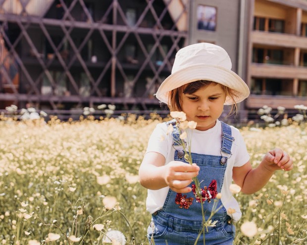 Kind in Blumenwiese hält eine Blume