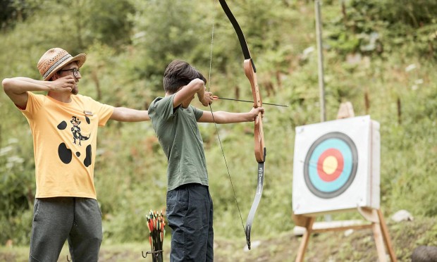 Betreuer zeigt einem Teenager das Bogenschießen
