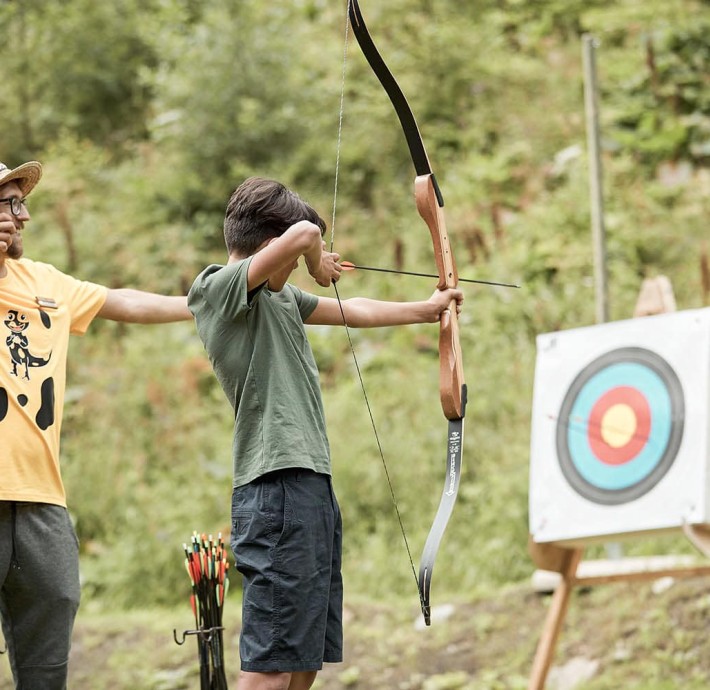 Betreuer zeigt einem Teenager das Bogenschießen