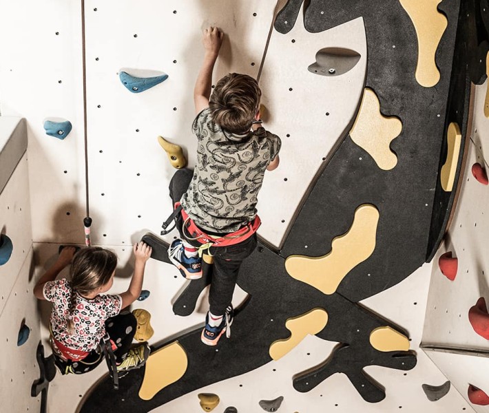 Kinder klettern die Kletterwand mit Flammi hinauf