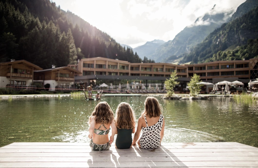 3 kleine Mädchen sitzen am Rande des Teiches und spritzen mit Wasser