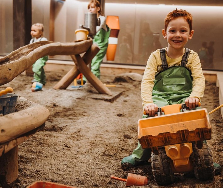 Kind spielt mit Bagger im Matschraum