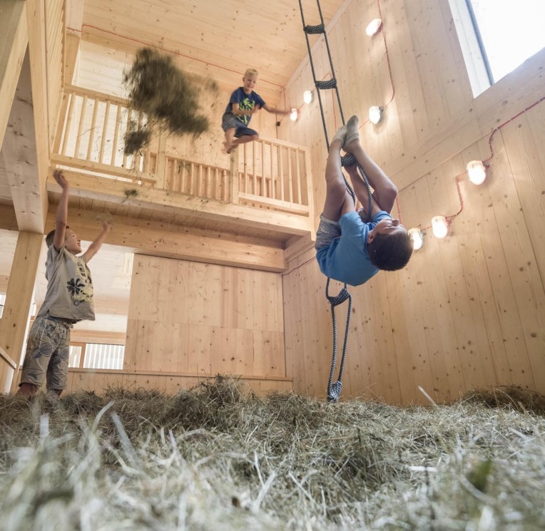 Kind spielt in der Scheune mit Heu