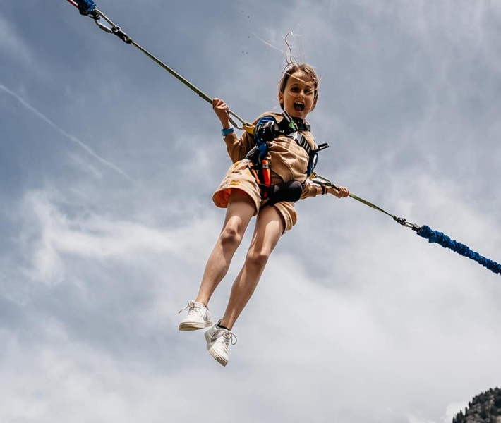 Kleines Mädchen schwebt in Luft angehängt an zwei Seilen & Gurte