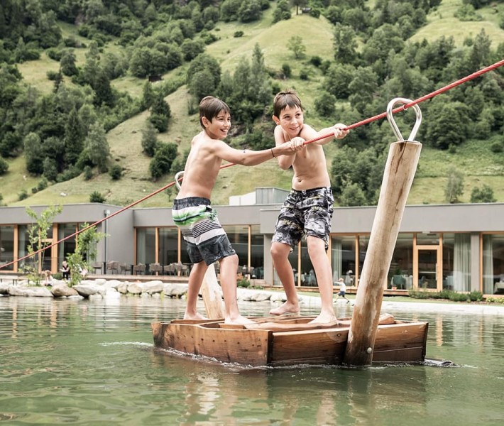 2 Jungs ziehen sich auf dem Floß vom einen Ende zum anderen des Sees