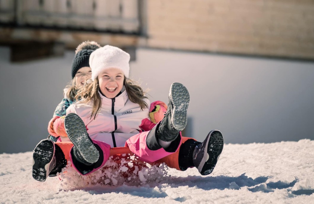 2 Kinder rodeln den Hang hinab