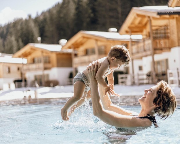 Mama und Baby schwimmen im Outdoor Infinity Pool des Familien-Wellnesshotel Feuerstein in Südtirol