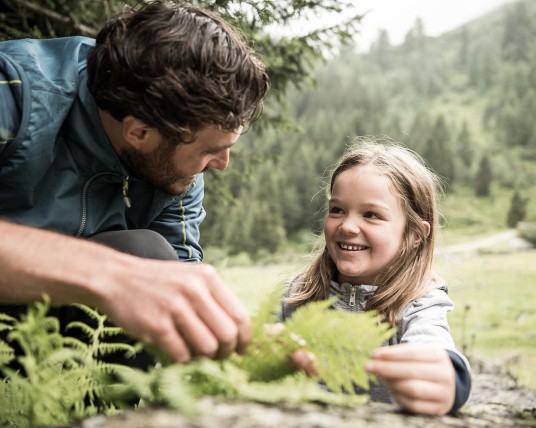Tochter und Vater beim Wandern entdecken verschiedene Pflanzen
