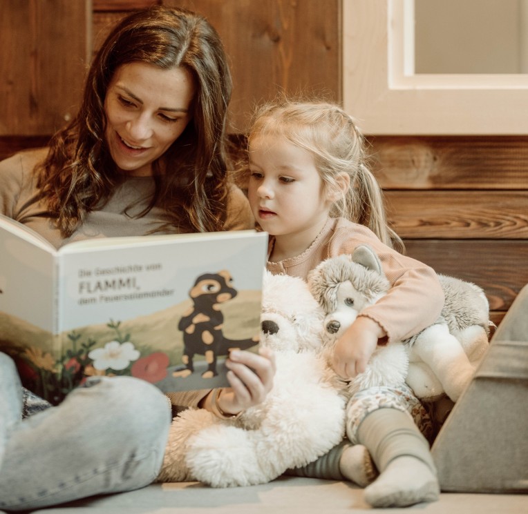 Eine Mutter liest mit ihrem Kind in einer gemütlichen Spielecke ein Buch