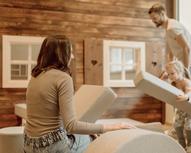 Zwei Kinder spielen mit großen weichen Bausteinen in einem Holzspielzimmer.