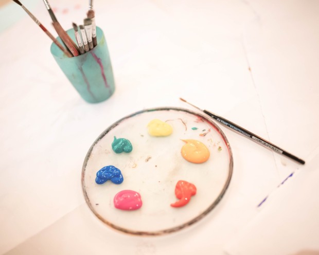 Ein Tisch mit Wasserfarben und einem Glas Wasser für kreative Malaktivitäten.