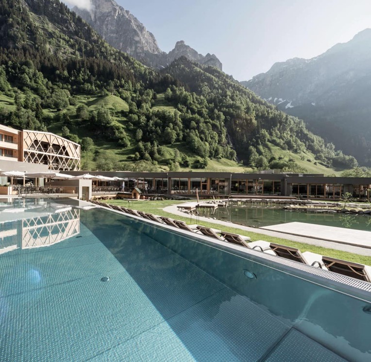 Der Outdoor Infinity Pool mit beeindruckendem Bergblick im Feuerstein, dem Kinderhotel mit Wasserrutsche in Südtirol