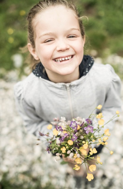 Kleines Kind lächelt und hält Blumen in der Hand