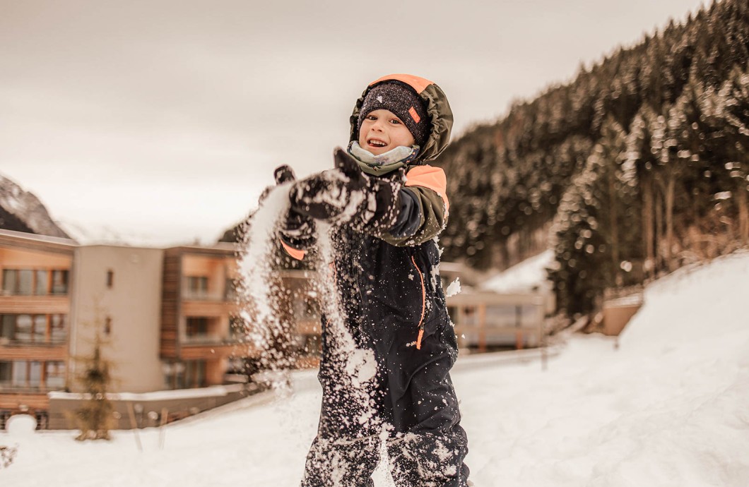 Klener Junge wirft Schnee in die Luft