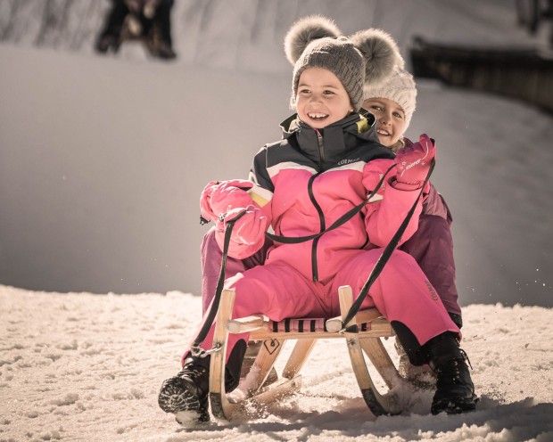2 kleine Kinder rodeln den Hügel hinunter
