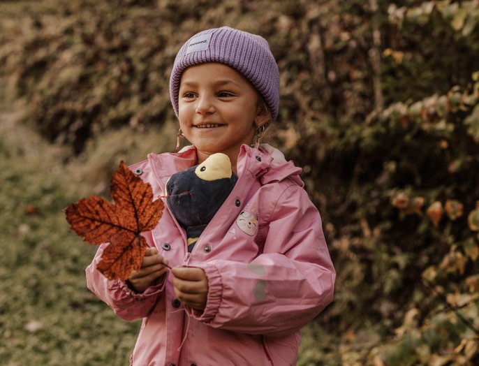 Kleines Kind mit Stofftier und großes Blatt von einem Baum